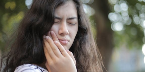 jaw pain woman holding jaw due to jaw pain