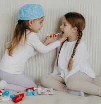 child dressed as dentist and playing with another child